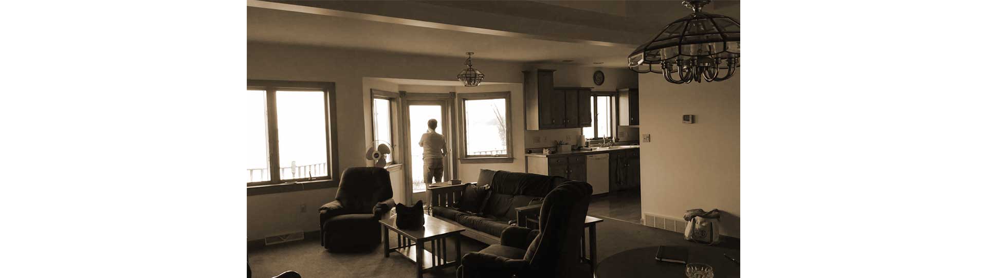 View from existing living room toward lake showing dated interior and the existing windows' limited lake views