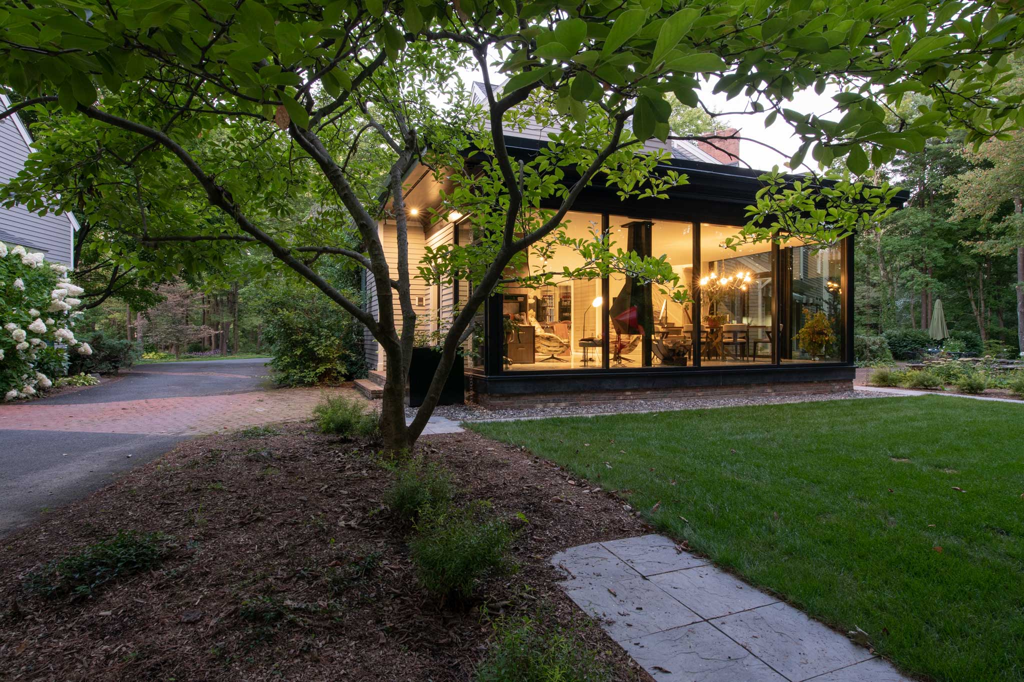 Exterior view of Outside In House from the back showing the interior of the addition as well as the landscaping blending into the design of the home.