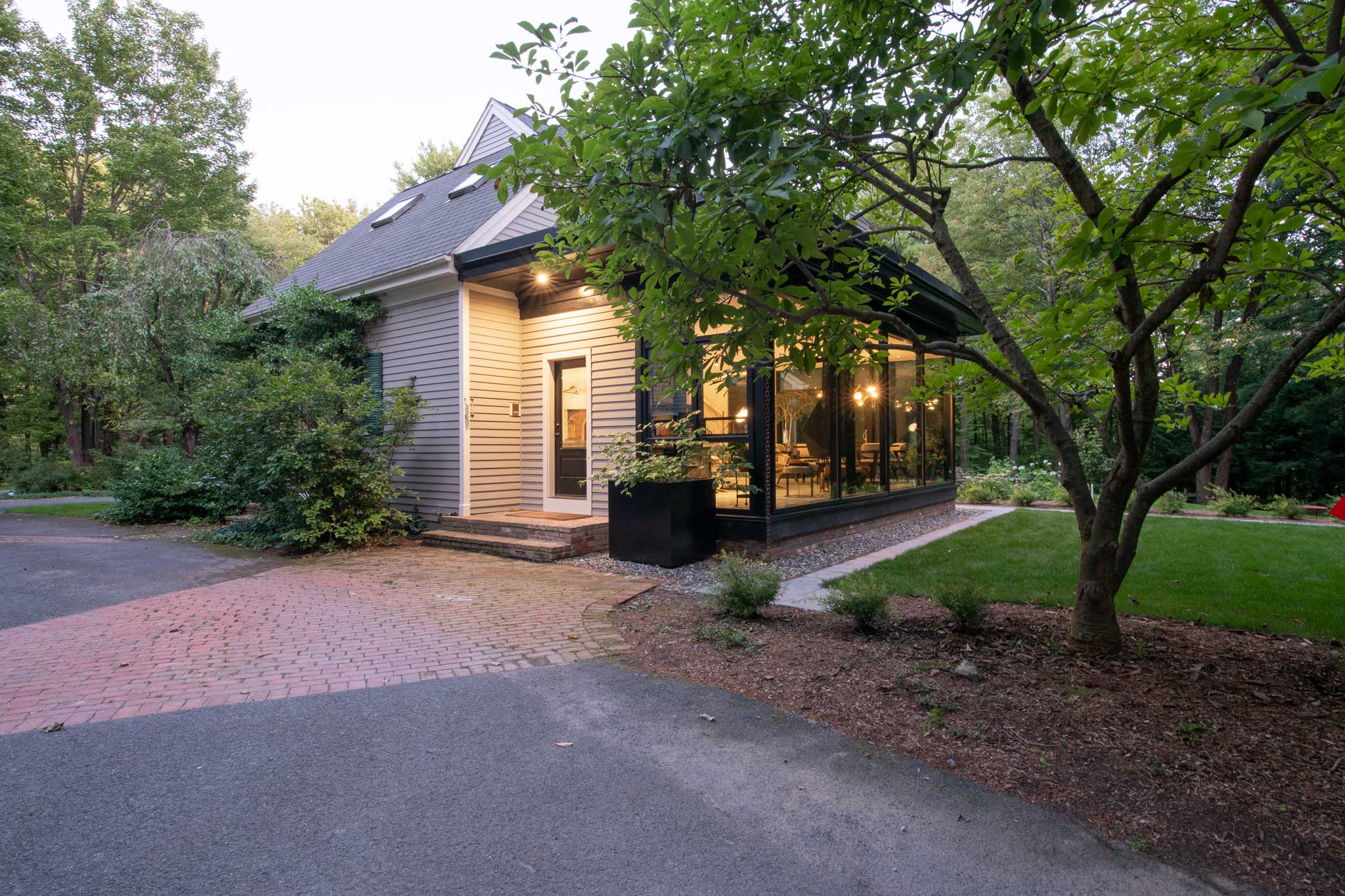 Exterior view of Outside In House from the driveway showing landscaping blending into the design of the home.
