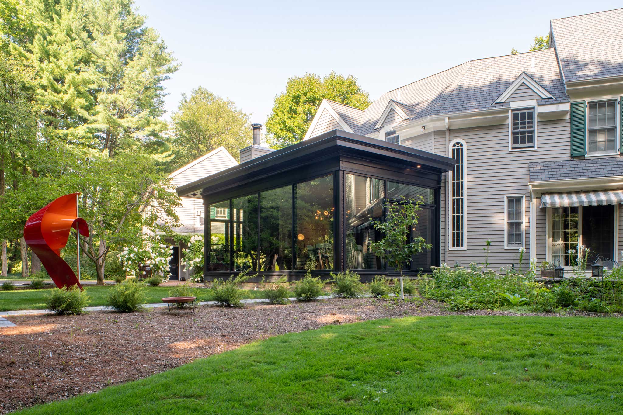 Exterior view of the modern addition showcasing artwork in the exterior landscaping.