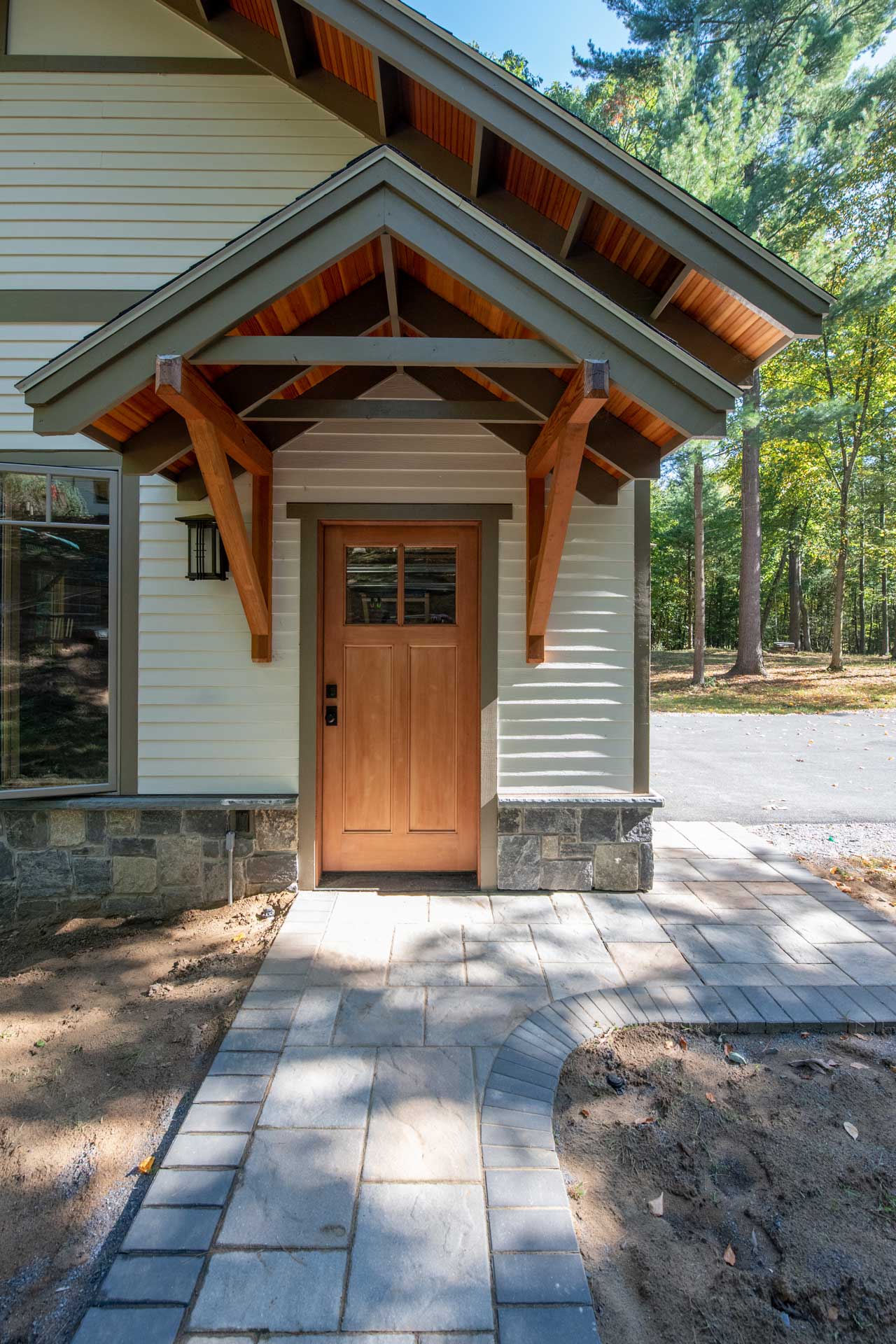 A natural wood beadboard canopy supported by natural timber brackets contrasts earth tone siding and trim to emphasize the entry